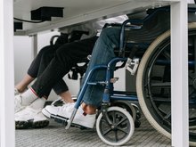 unter einem Schultisch sieht man, dass Schüler*innen sowohl auf Stühlen als auch im Rollstuhl sitzen